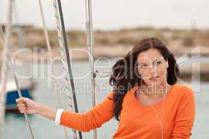 Attractive woman standing on sailing boat with headphones
