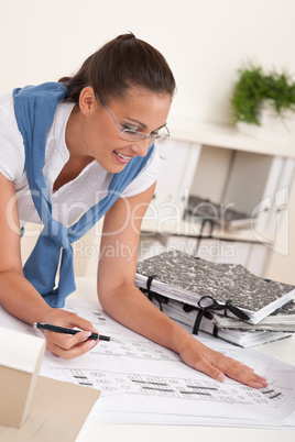 Smiling female architect watching plans