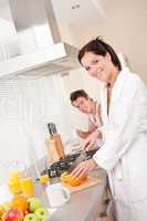 Smiling woman cutting oranges in the kitchen