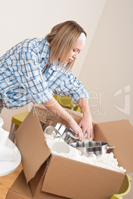 Moving house: Woman unpacking box with pot