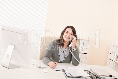 Smiling young business woman on phone at office