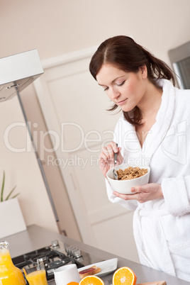 Happy woman eating cereals for breakfast in kitchen