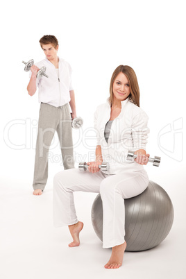 Young couple with weights and fitness ball on white