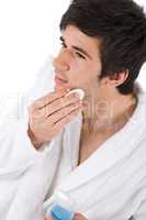 Facial care - Young man cleaning face with lotion