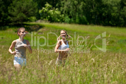 Two young woman jogging in a meadow