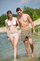 Happy couple in swimwear walk in lake