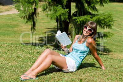 Happy young woman with book in park