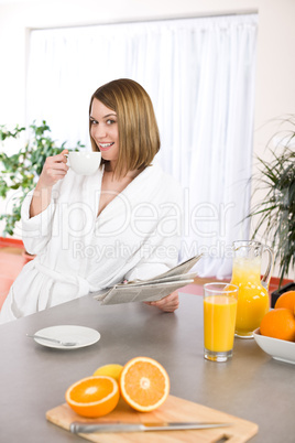 Breakfast - Smiling woman reading newspaper in kitchen