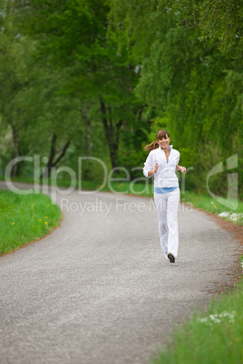 Jogging - sportive woman running on road in nature