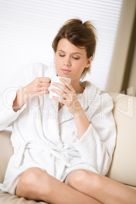 Young woman in white bathrobe with coffee