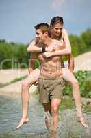 Piggyback - happy couple enjoy sun at lake