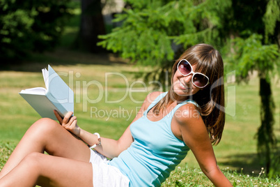 Happy young woman with book in park