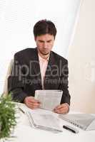 Successful modern businessman with laptop and newspaper