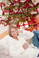 Blond smiling woman in front of Christmas tree