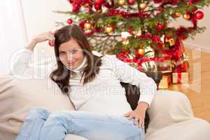 Smiling young woman in front of Christmas tree