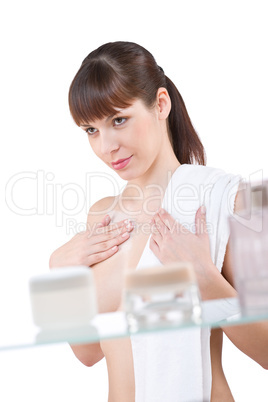 Body care: Young woman applying cream in bathroom