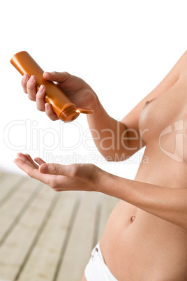 Topless woman with suntan lotion on beach