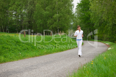 Jogging - sportive woman running on road in nature