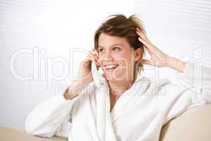 Happy woman in white bathrobe with phone