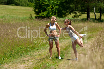 Two young women exercising in a meadow