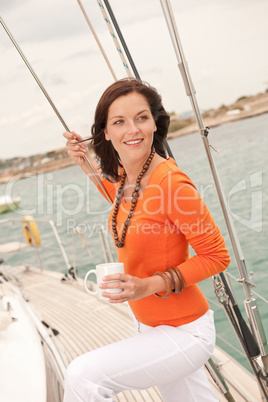 Young woman standing on sailing boat with cup of coffee