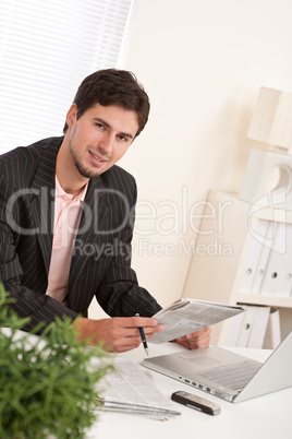 Successful modern businessman with laptop and newspaper