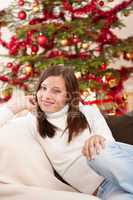 Smiling young woman in front of Christmas tree