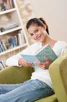 Students - Happy teenager with book sitting on armchair