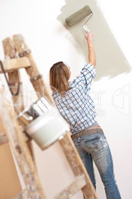 Home improvement: Cheerful woman with paint roller and ladder