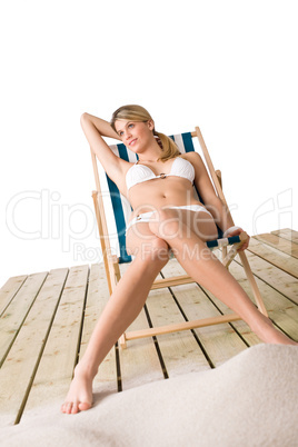 Beach - Woman in bikini sunbathing on deck chair with sand