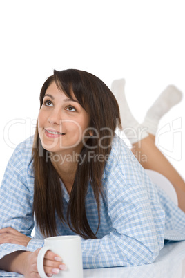 Happy young woman with coffee in pajamas