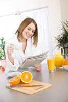 Breakfast - Smiling woman reading newspaper in kitchen