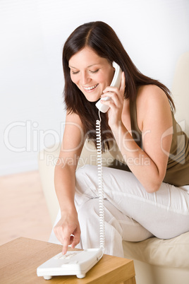 On the phone home: smiling woman dialing number calling
