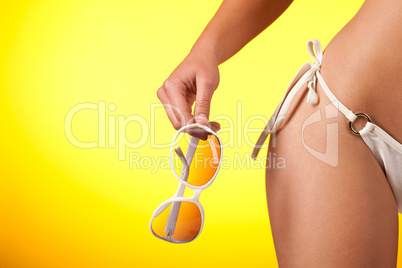 Part of female body with white bikini and sunglasses