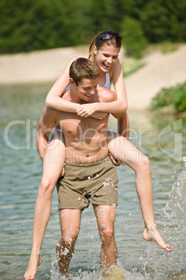 Piggyback - happy couple enjoy sun at lake
