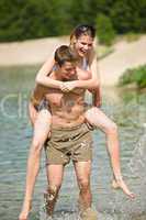 Piggyback - happy couple enjoy sun at lake