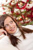 Smiling young woman in front of Christmas tree