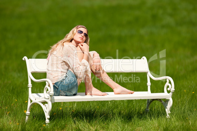 Spring - Young woman relaxing on bench in meadow
