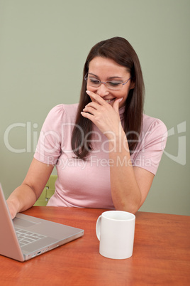 Smiling secretary with coffee and laptop at office