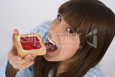 Happy teenager in pajamas eating healthy toast