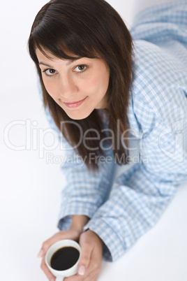 Happy young woman with coffee in pajamas