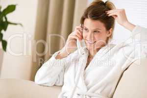 Happy woman in white bathrobe with phone home
