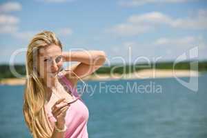 Blond woman hold sunglasses on beach
