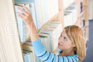 Student in library - happy woman reach for book