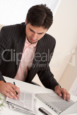 Successful modern businessman with laptop and newspaper