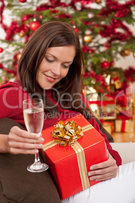 Smiling woman with Christmas present and glass of champagne