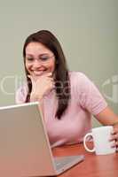 Smiling secretary with coffee and laptop at office