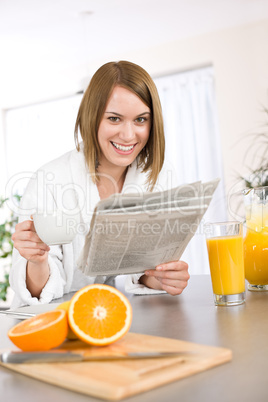 Breakfast - Smiling woman reading newspaper in kitchen