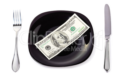 Banknote on a black plate with knife and fork