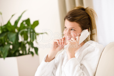 Happy woman in white bathrobe with phone home